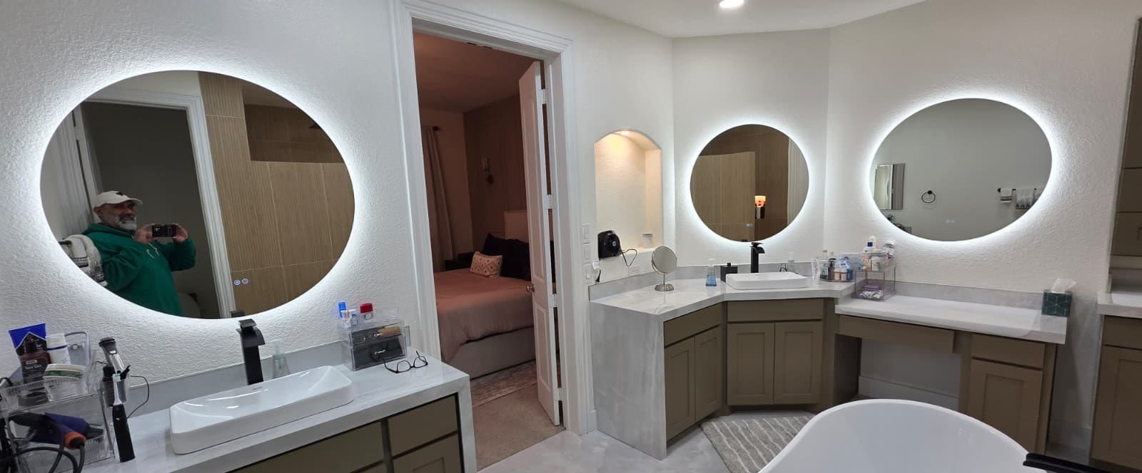 Finished primary bathroom with large-format tile and backlit round mirrors